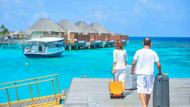 A couple arriving at a luxurious Maldives resort dock with luggage, capturing a tropical vacation vibe., tags: und - pexel